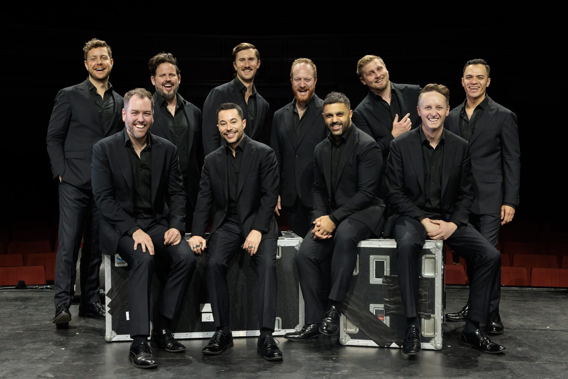 Die Ten Tenors: Gruppenfoto der zehn Sänger in schwarzen Anzügen, posierend und lächelnd.