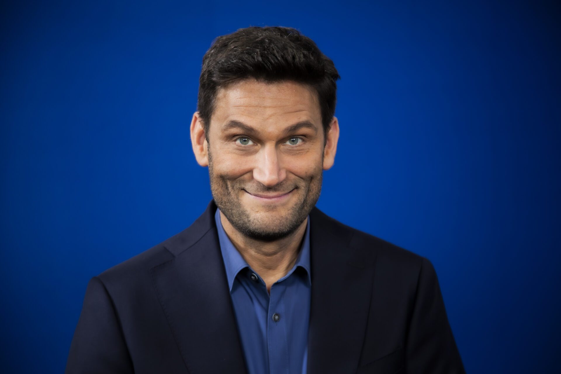 Pressefoto CH neutrales Foto1 ©keine Namensnennung erforderlich Pressefoto Christian Ehring: Porträt des Kabarettisten vor blauem Hintergrund.