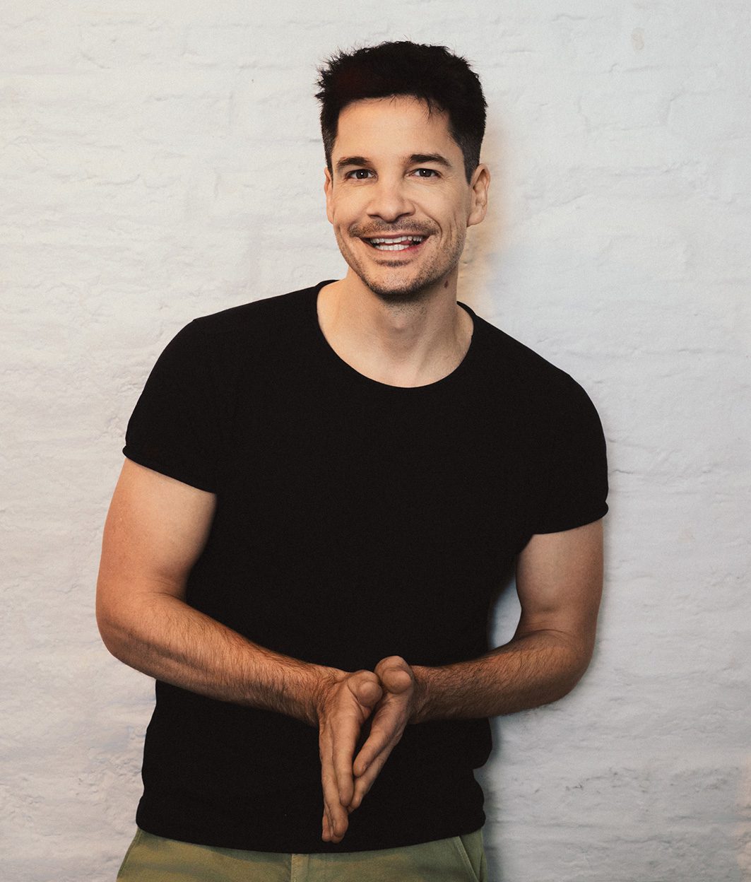 Alain_Frei_(c)Ramiro Simone – 2_web Alain Frei, Frontalansicht: Lachender Mann vor weißer Wand. Portrait von Ramiro Simone.