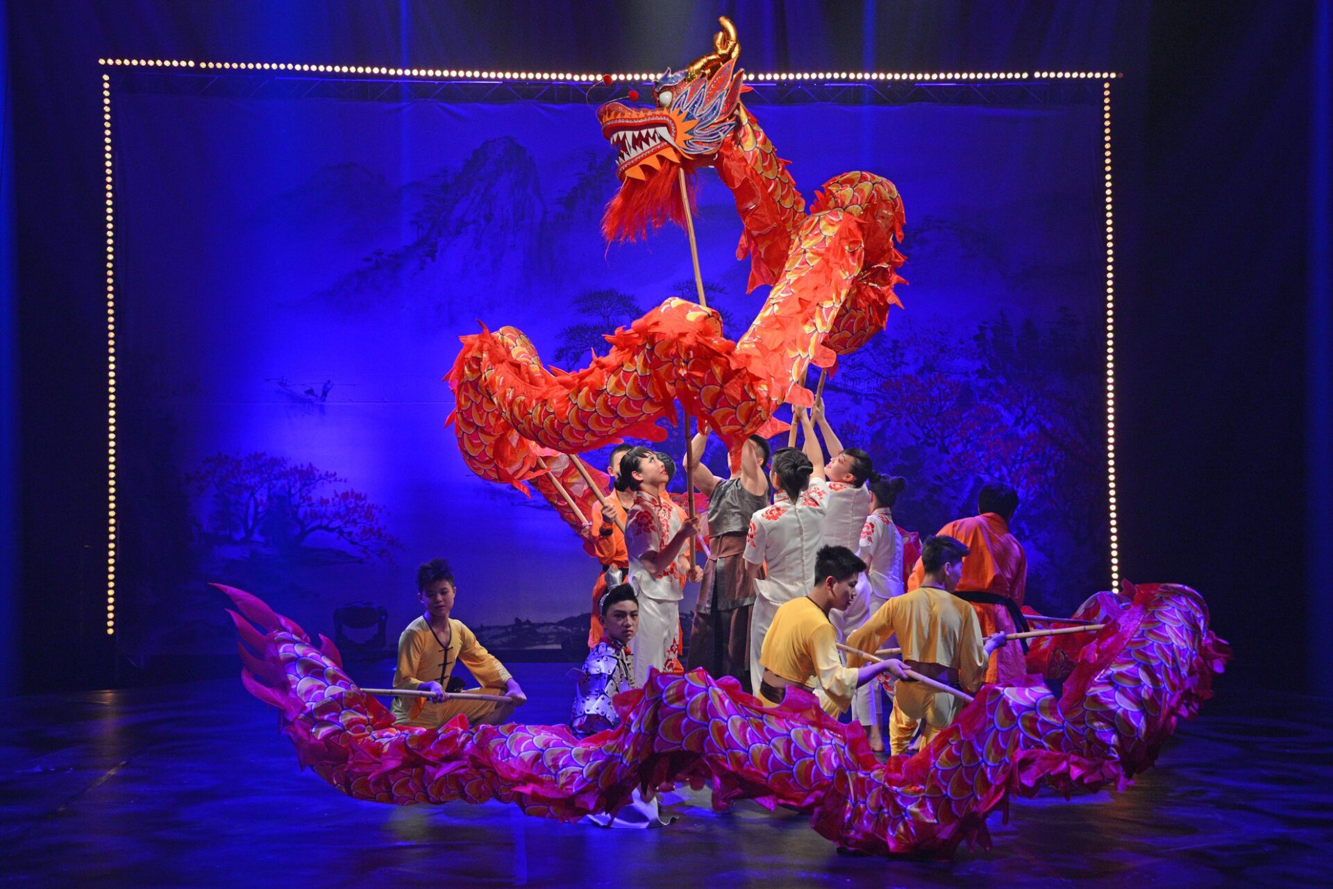 CNC 57 dragon Chinesischer Nationalcircus Drache: Gruppe von Artisten führt einen roten, kunstvollen Drachen auf einer Bühne auf.