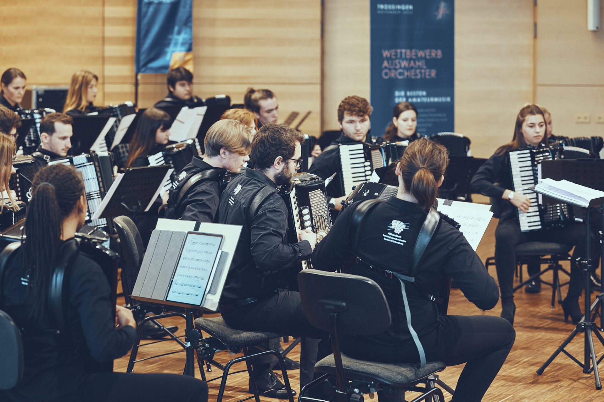 Junge Musikerinnen und Musiker eines Auswahlorchesters mit Akkordeons und Notenpulten im Wettbewerb.